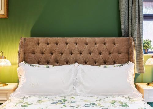 a bed with a brown headboard and two white pillows at Beech Tree Park Cottages in Hatfield