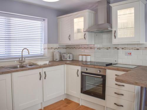 a kitchen with white cabinets and a sink at Sea Breeze in Kessingland