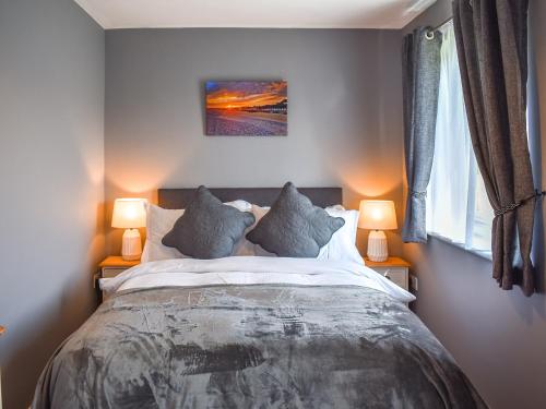 a bedroom with a large bed with two lamps at Sea Breeze in Kessingland