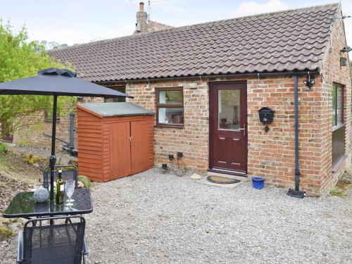 a small brick house with an umbrella in front of it at Bellwood House Annexe in Felixkirk