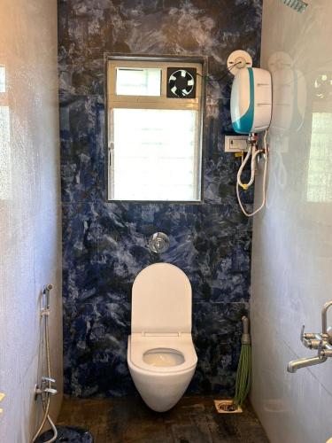 Un baño con inodoro y ventana. en Vrindavan Hotel, en Malvan
