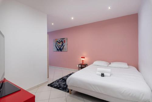 a bedroom with a white bed and a pink wall at Maison Frappaz in Villeurbanne
