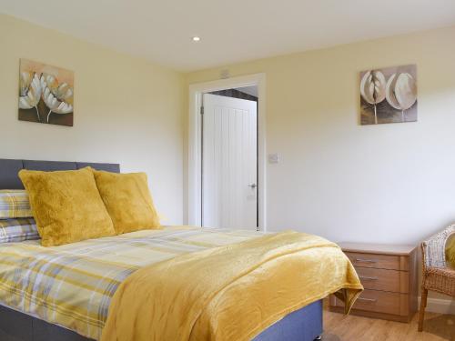 a bedroom with a bed with a yellow blanket at Sherwood Forest Lodge 2 in Clipstone