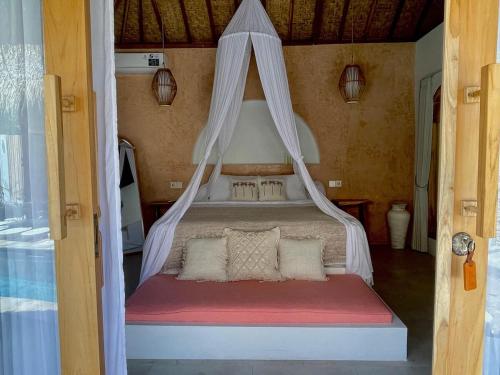 a bed with a mosquito net in a room at Villa Nyantara in Gili Air