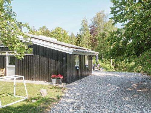 a black house with a gravel driveway next to a building at 8 person holiday home in Græsted-By Traum in Udsholt Sand