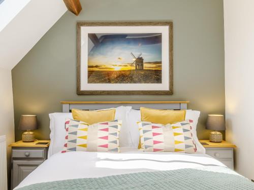 a bedroom with a bed and a picture of a windmill at Wool Loft in Kemble