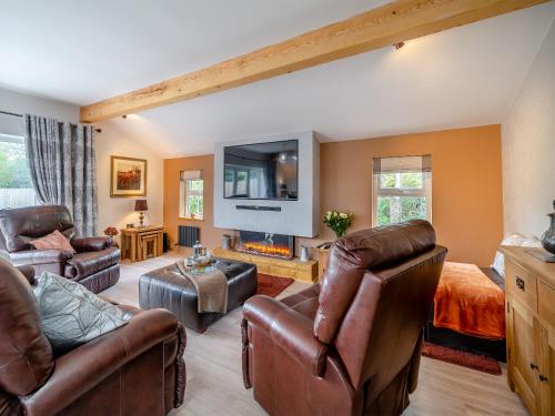 a living room with leather furniture and a flat screen tv at Briar Cottage in Great Eccleston