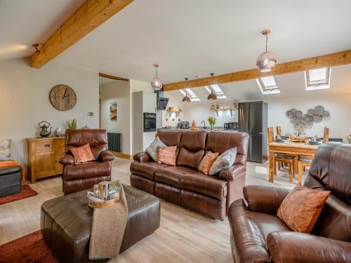 a living room with leather furniture and a kitchen at Briar Cottage in Great Eccleston