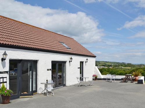 a white building with tables and chairs outside of it at Caddys Cottage - Uk6714 in Lydstep