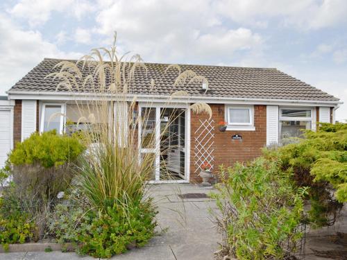 a brick house with a window and bushes at Fairlawns in Fairbourne