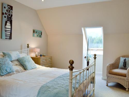 a bedroom with a bed and a chair and a window at Lia Fail in Ballachulish