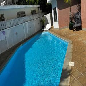 a large blue swimming pool next to a building at 2 Bedroom Lotus Apt Flic en Flac in Flic-en-Flac