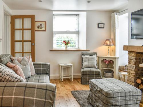 a living room with a couch and two chairs at Bathurst Cottage in Scarcliffe