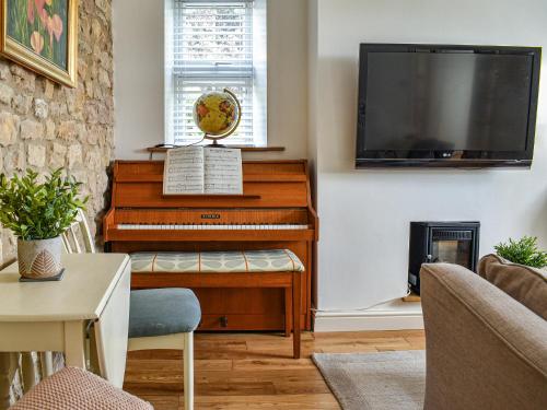 a living room with a piano and a flat screen tv at Bathurst Cottage in Scarcliffe