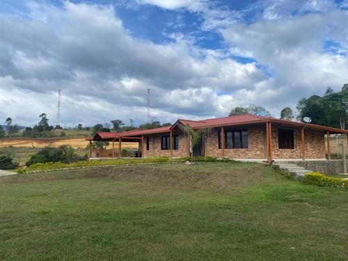 una casa de ladrillo con un patio de hierba delante de ella en Parcela el privilegio, en Totoró
