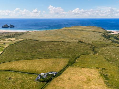 una vista aérea de un campo verde con el océano en The Old Stable, en Holywell Bay