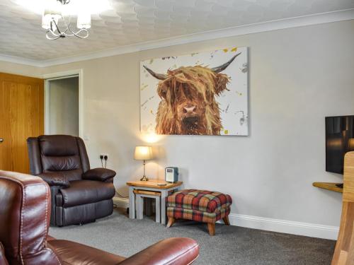 una sala de estar con una silla y una foto de una vaca en The Granary - Uk47428, en Bewaldeth