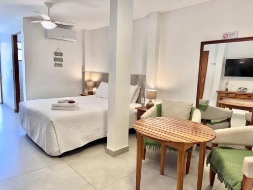 a bedroom with a bed and a table and chairs at Bella Buzios Apartamentos in Búzios