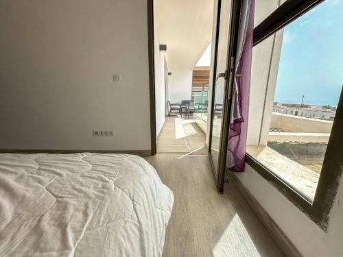 Un dormitorio con una cama y una ventana grande. en Spacious Duplex Sea & Waves, en Tamraght Ouzdar