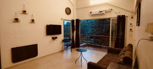 a living room with a couch and a television and a balcony at Hillview Escape - Cozy 1bhk apartment in Karjat