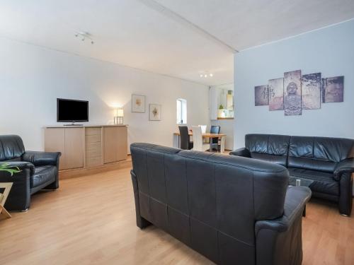 a living room with leather furniture and a flat screen tv at Bungalow in Landgraaf with terrace in Landgraaf