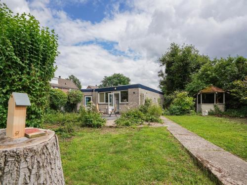 a house in a yard with a tree stump at Bungalow in Landgraaf with terrace in Landgraaf