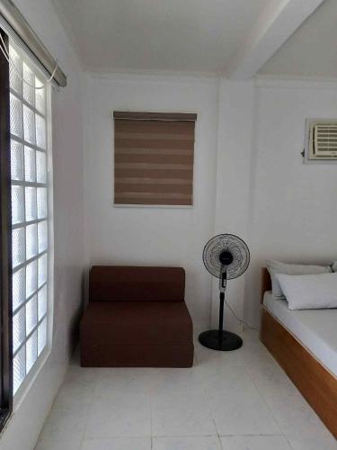 a bedroom with a bed and a chair and a fan at A & L Resort - Sea & Mountain View in Looc