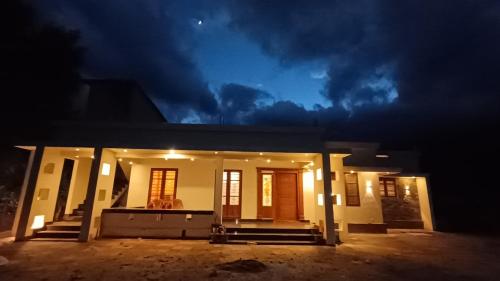 une maison éclairée la nuit avec un ciel sombre dans l'établissement Dolmens castle, à Maraiyūr