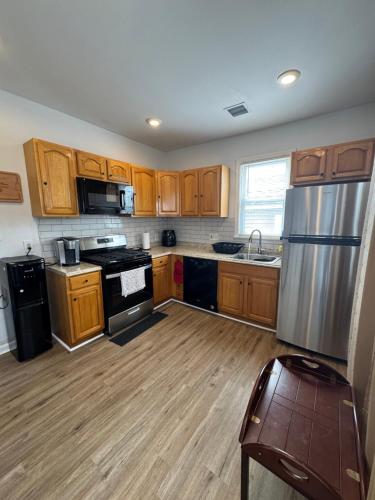 une cuisine avec des armoires en bois et un réfrigérateur en acier inoxydable dans l'établissement Kennedy House on Melrose Ave, à Atlantic City