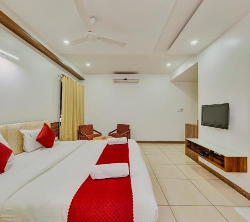 a hotel room with a large bed with a red blanket at Hotel Woodland in Kolhapur