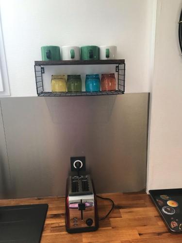 a kitchen with a shelf with cups and a toaster at Charmant Studio indépendant in Louvres