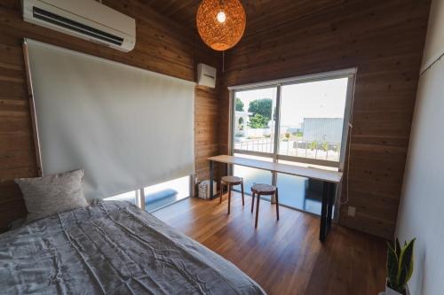 a bedroom with a bed and a desk and a window at Haruhiya in Ishigaki Island