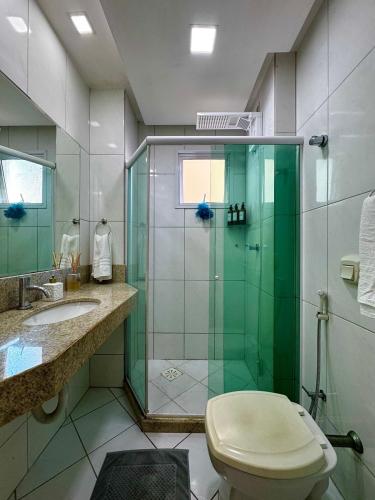 ein Badezimmer mit Dusche, Toilette und Waschbecken in der Unterkunft Apartamento lindo frente ao mar in Guarapari