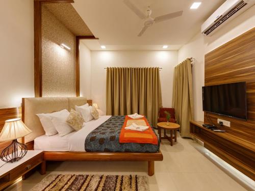 a hotel room with a bed and a flat screen tv at Hotel Woodland in Kolhapur