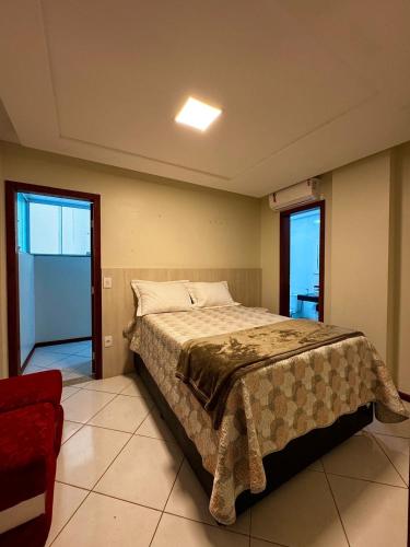 ein Schlafzimmer mit einem großen Bett und einem roten Stuhl in der Unterkunft Apartamento lindo frente ao mar in Guarapari