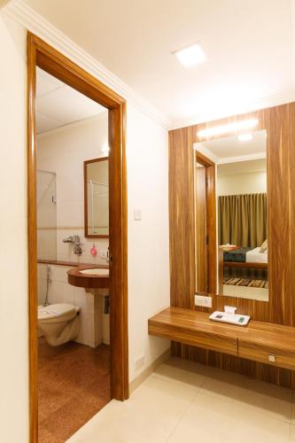 a bathroom with a toilet and a sink and a mirror at Hotel Woodland in Kolhapur