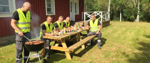 a group of men in yellow vests sitting at a picnic table at Spacious Cabin for Work Crews, 10 Beds! in Ingelstad