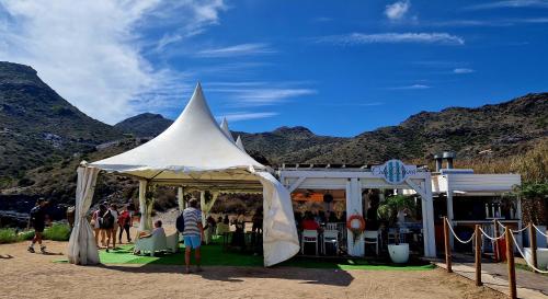 a white tent with people standing under it with mountains at Cabo de Palos Apartment in Cabo de Palos