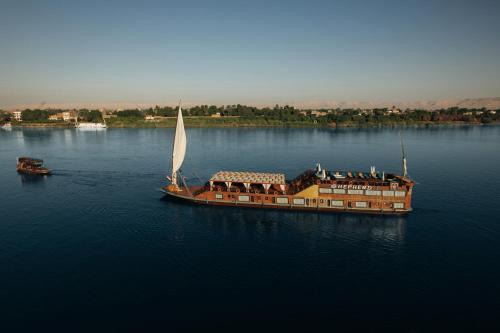 a large boat with a sail in the water at Shepherd I Dahabya in Esna