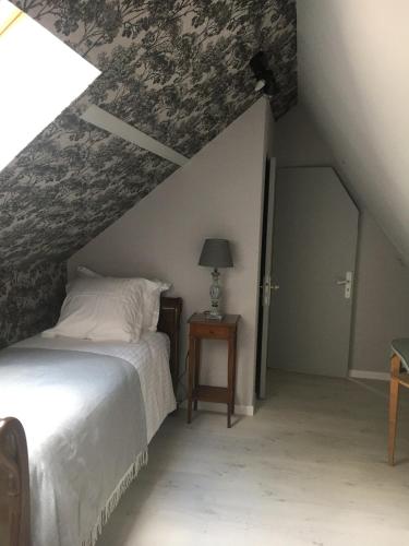 a bedroom with a bed in a attic at Le Logis Fleurs et jardins de Pitry in Thierville