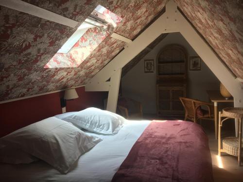 a bedroom with an attic with a bed and a window at Le Logis Fleurs et jardins de Pitry in Thierville