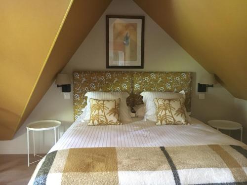 a bedroom with a large bed in a attic at Le Logis Fleurs et jardins de Pitry in Thierville