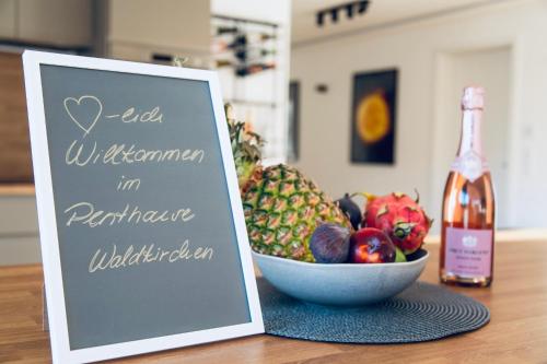 a sign next to a bowl of fruit and a bottle of wine at Modernes Penthouse mit Bergpanorama & großer Terrasse, für bis zu 8 Personen in Waldkirchen
