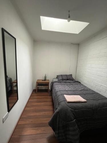 a small bedroom with a bed and a mirror at Hostel Tu Espacio RE - Habitaciones cerca del Aeropuerto in Santiago