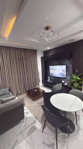 a living room with a table and a tv at One bedroom apartment with massage chair and PS5 in Lagos