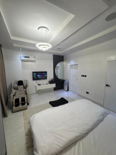 a white bedroom with a large bed and a tv at One bedroom apartment with massage chair and PS5 in Lagos