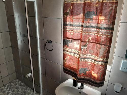 a shower curtain in a bathroom with a toilet at Farmhouse Boutique Backyard Rooms in Outjo