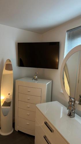 a bathroom with a mirror and a dresser with a sink at LUXURY Apartment Belfast City Centre overlooking Custom House Square in Belfast