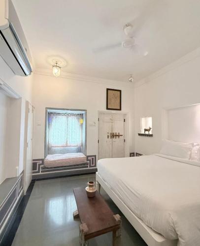 a white bedroom with a large bed and a window at Little Garden Guest House in Udaipur