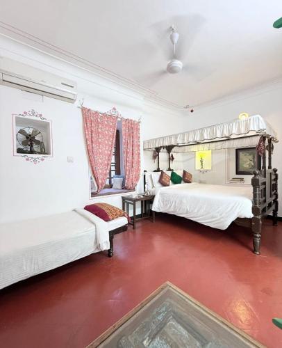 a bedroom with two beds and a red floor at Little Garden Guest House in Udaipur
